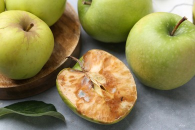 Photo of Spoiled apple and good ones on grey table, closeup
