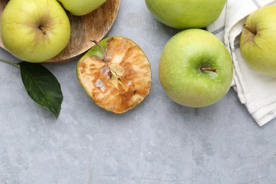 Photo of Spoiled apple and good ones on grey table, flat lay. Space for text