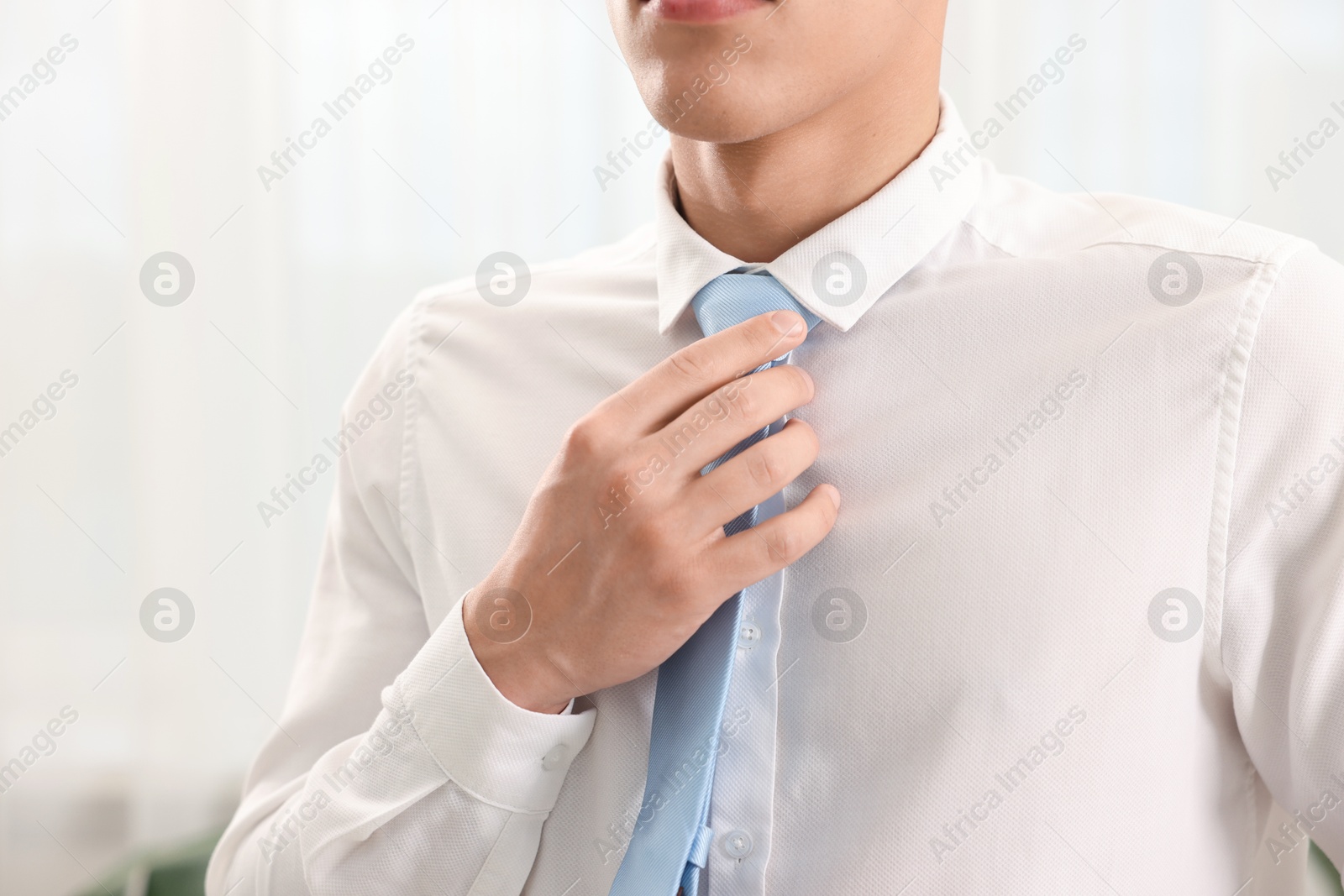 Man tying stylish necktie at home, closeup Photo of Man tying stylish necktie at home, closeup
