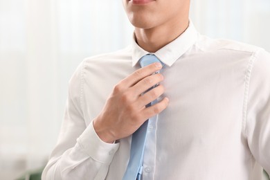 Photo of Man tying stylish necktie at home, closeup