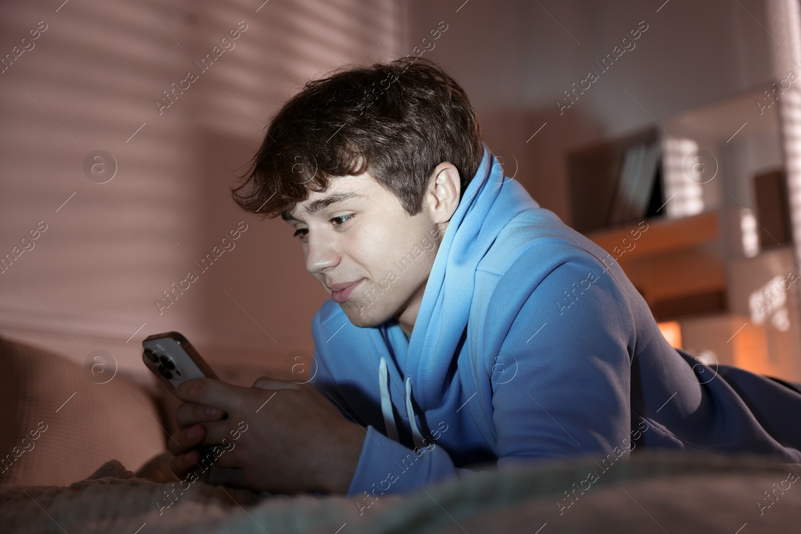 Teenage boy using smartphone on bed at home Photo of Teenage boy using smartphone on bed at home