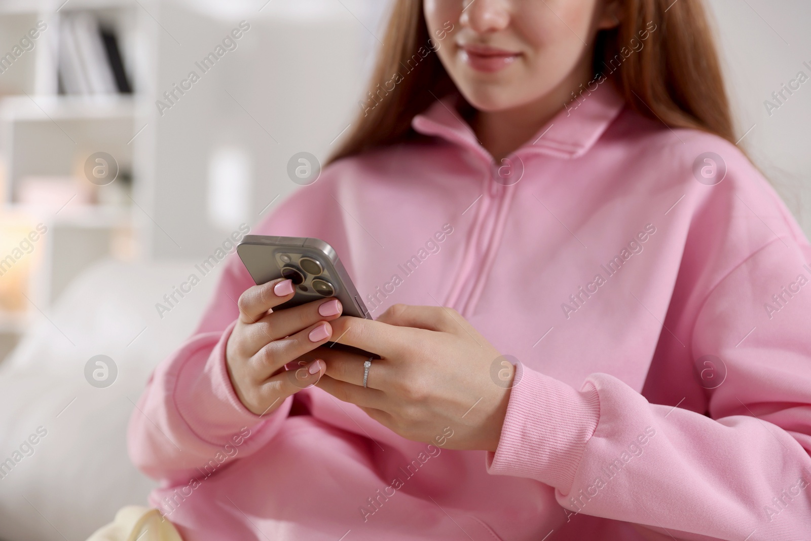 Photo of Teenage girl using smartphone at home, closeup