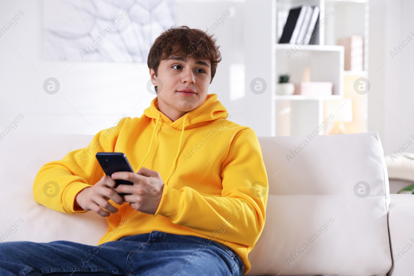 Teenage boy using smartphone on sofa at home Photo of Teenage boy using smartphone on sofa at home