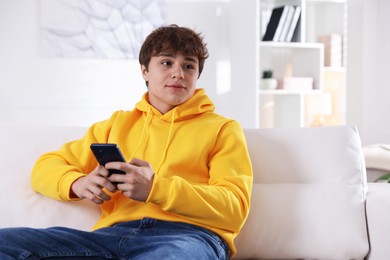 Photo of Teenage boy using smartphone on sofa at home