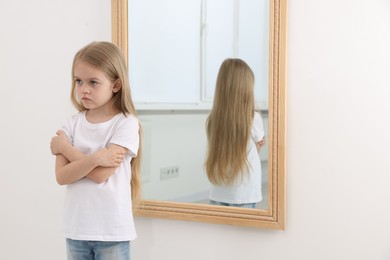 Photo of Upset little girl near mirror at home