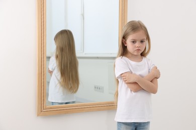 Photo of Upset little girl near mirror at home