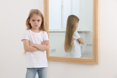 Photo of Upset little girl near mirror at home