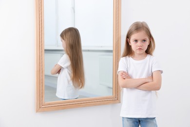 Photo of Upset little girl near mirror at home