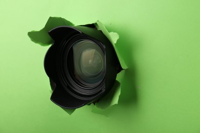 Photo of Hidden camera lens through torn hole in green paper