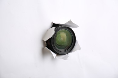 Photo of Hidden camera lens through torn hole in white paper