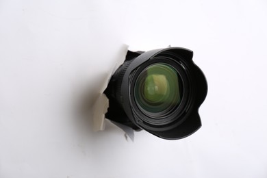 Photo of Hidden camera lens through torn hole in white paper