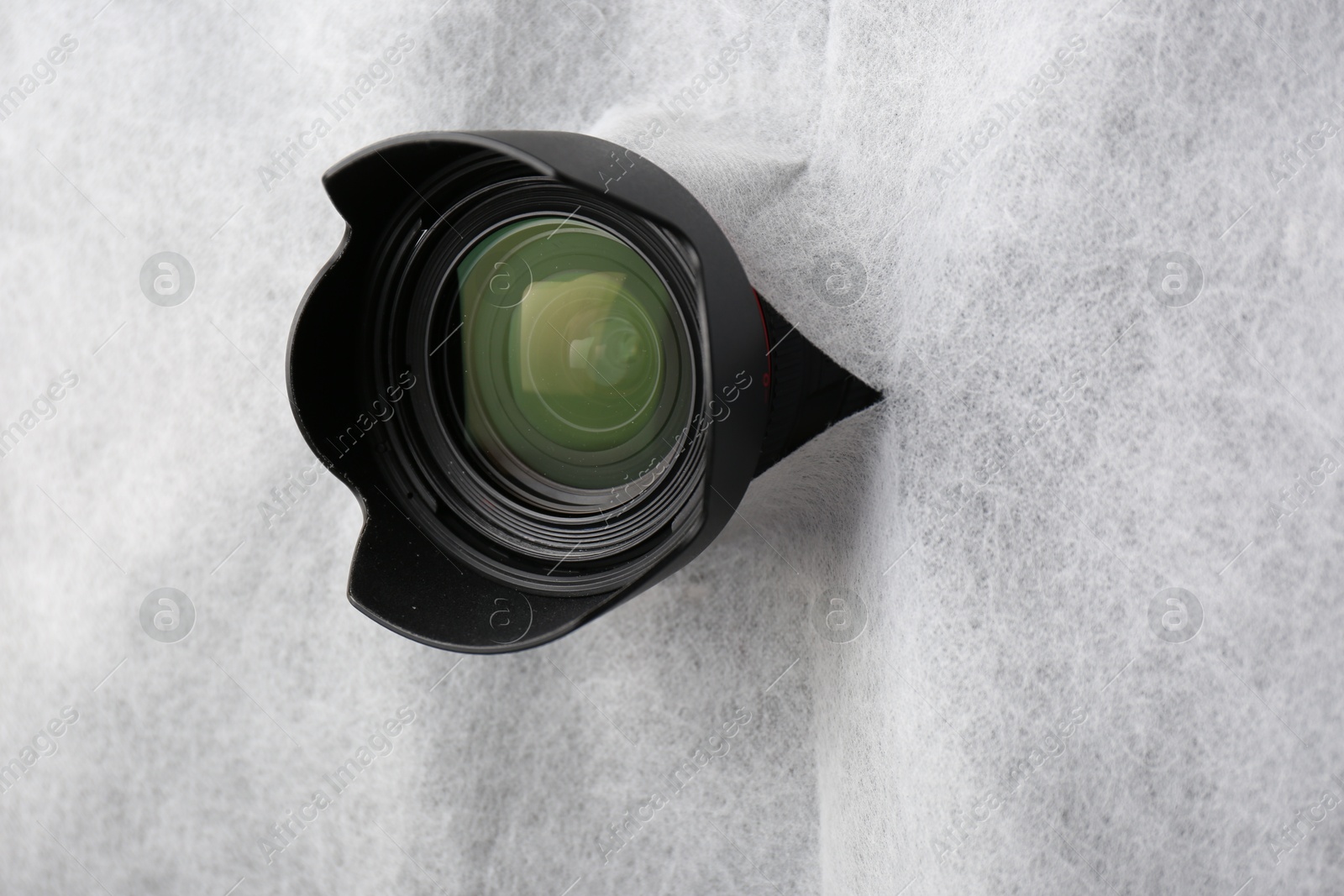 Hidden camera lens through torn hole in white fabric Photo of Hidden camera lens through torn hole in white fabric