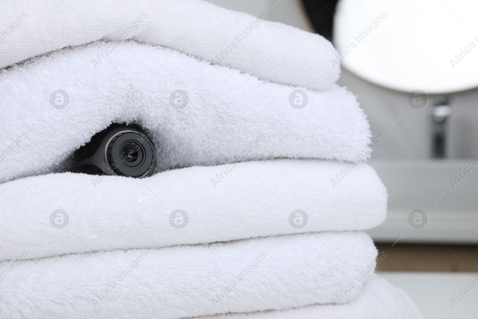 Camera hidden between towels in bathroom, space for text Photo of Camera hidden between towels in bathroom, space for text