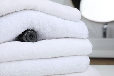 Photo of Camera hidden between towels in bathroom, space for text