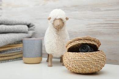 Photo of Camera hidden in wicker box on white table, space for text