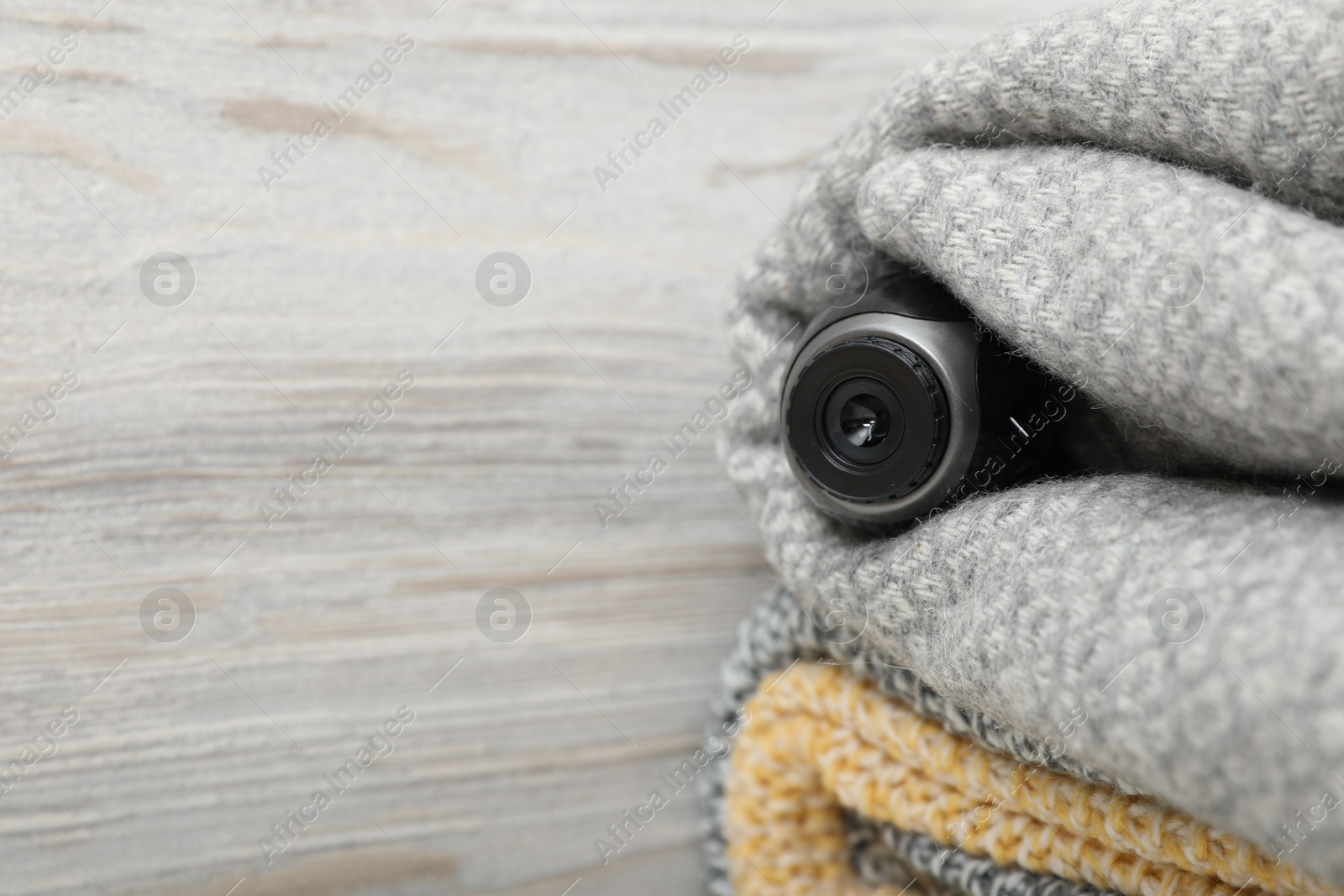 Camera hidden in plaid near wooden wall, space for text Photo of Camera hidden in plaid near wooden wall, space for text