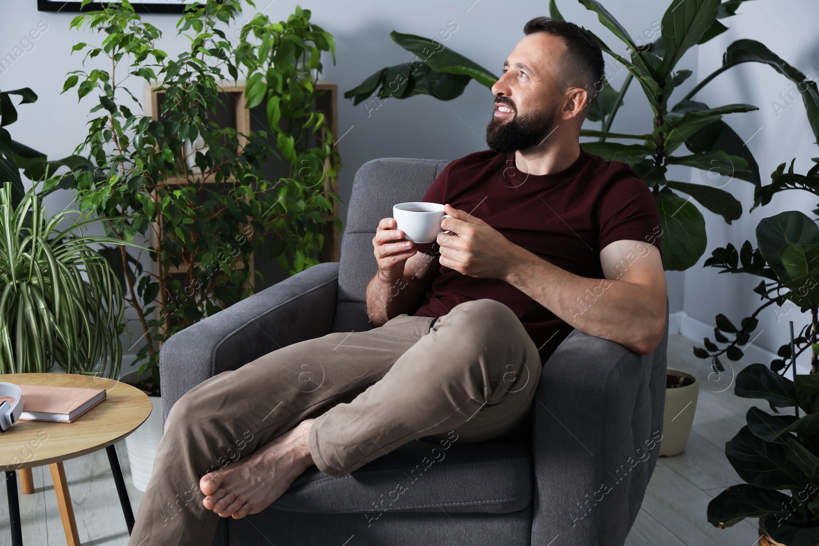 Harmony. Man with cup of drink in armchair at home Photo of Harmony. Man with cup of drink in armchair at home