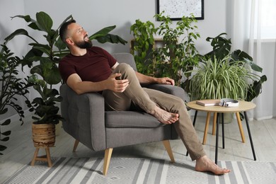 Photo of Harmony. Man relaxing in comfortable armchair at home
