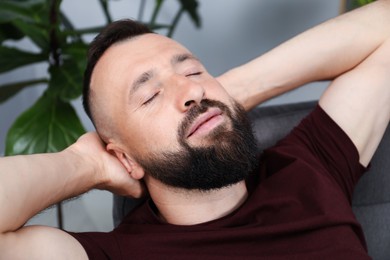 Photo of Harmony. Man relaxing in comfortable armchair at home