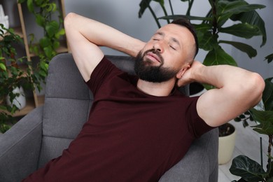 Photo of Harmony. Man relaxing in comfortable armchair at home