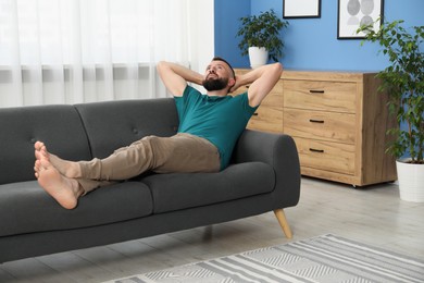 Photo of Harmony. Man relaxing on comfortable sofa at home