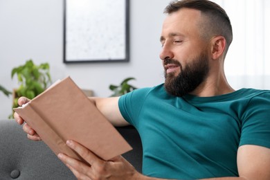 Photo of Harmony. Man reading book on sofa at home