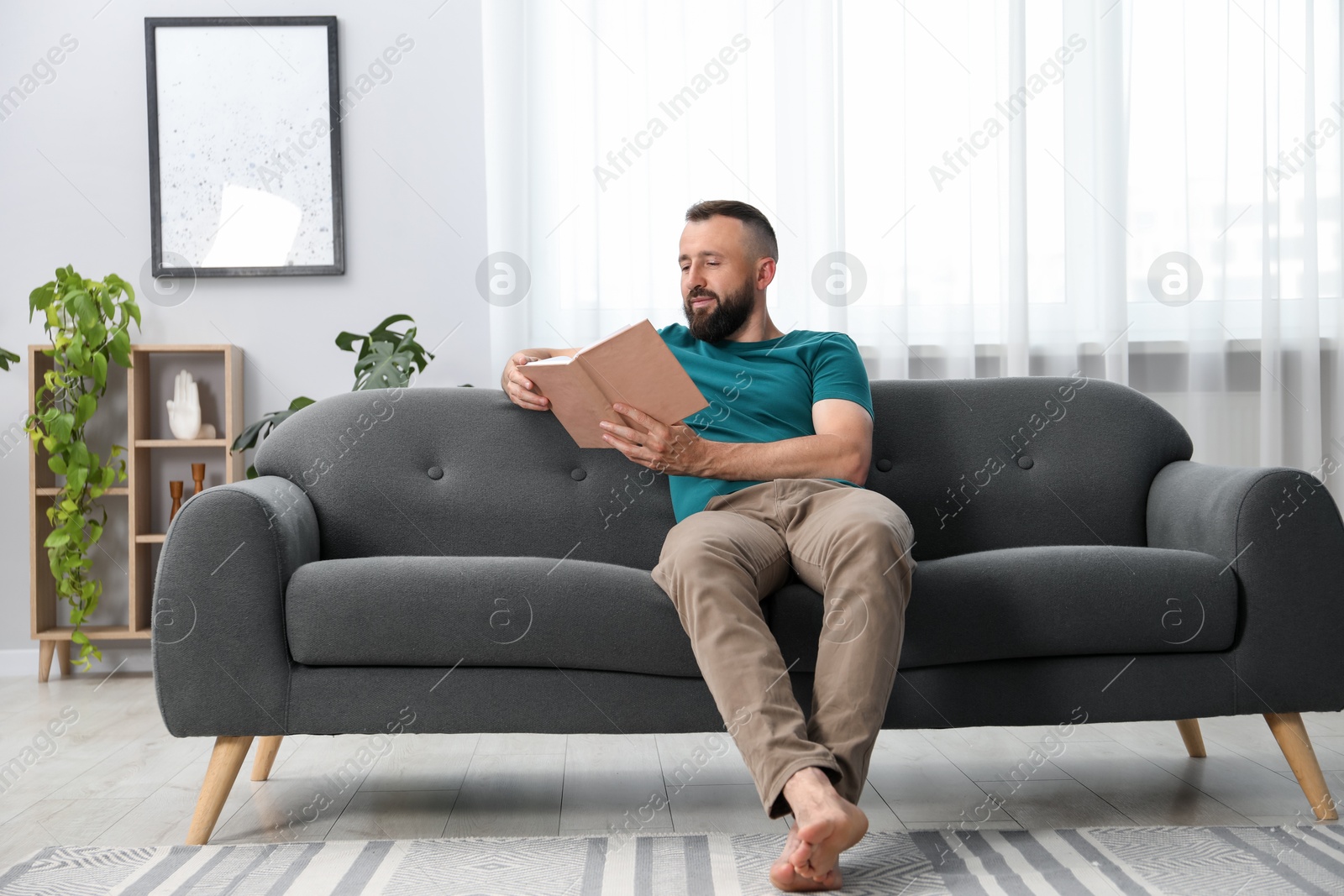 Harmony. Man reading book on sofa at home Photo of Harmony. Man reading book on sofa at home