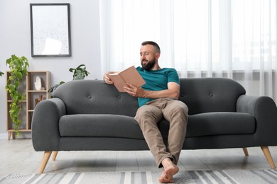 Photo of Harmony. Man reading book on sofa at home