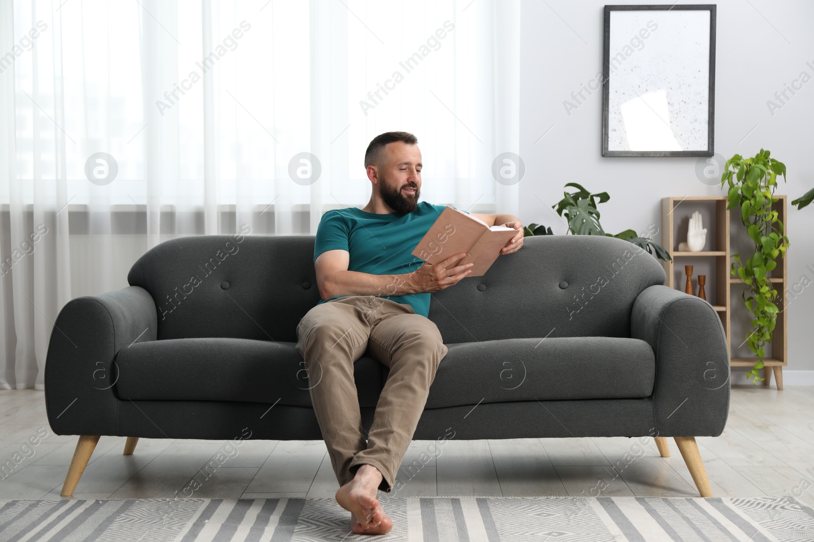 Harmony. Man reading book on sofa at home Photo of Harmony. Man reading book on sofa at home