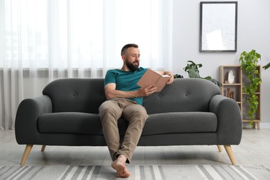 Photo of Harmony. Man reading book on sofa at home