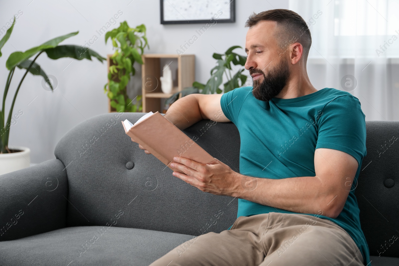 Harmony. Man reading book on sofa at home Photo of Harmony. Man reading book on sofa at home
