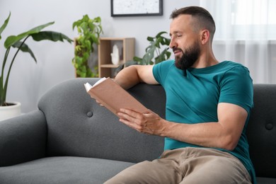 Photo of Harmony. Man reading book on sofa at home