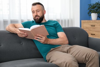 Photo of Harmony. Man reading book on sofa at home