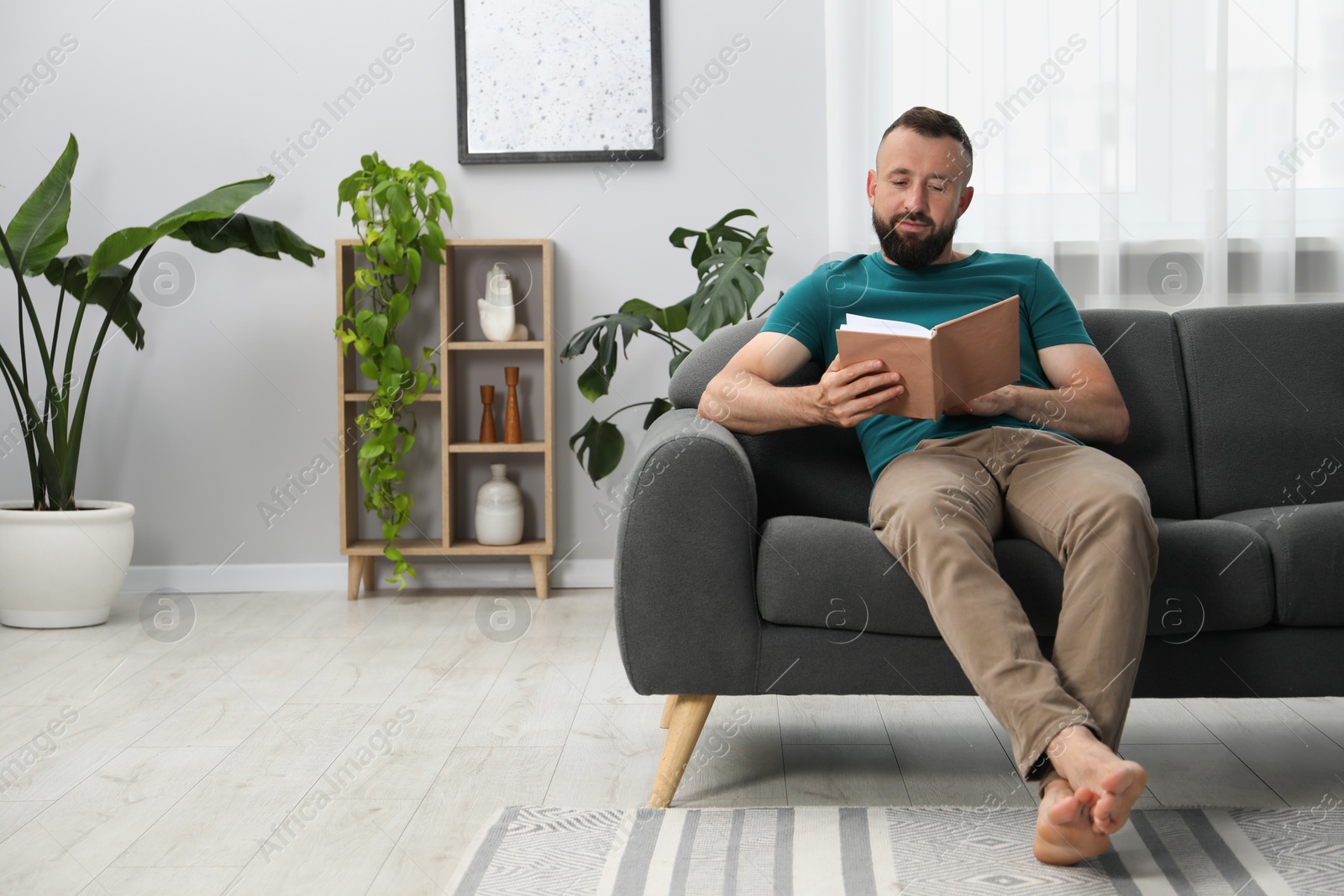 Harmony. Man reading book on sofa at home Photo of Harmony. Man reading book on sofa at home