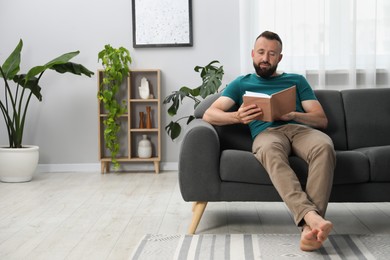 Photo of Harmony. Man reading book on sofa at home