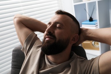 Photo of Harmony. Man relaxing in comfortable armchair at home