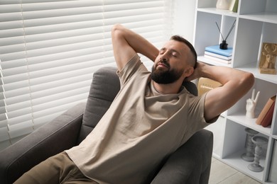 Photo of Harmony. Man relaxing in comfortable armchair at home