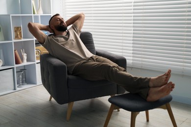 Photo of Harmony. Man relaxing in comfortable armchair at home