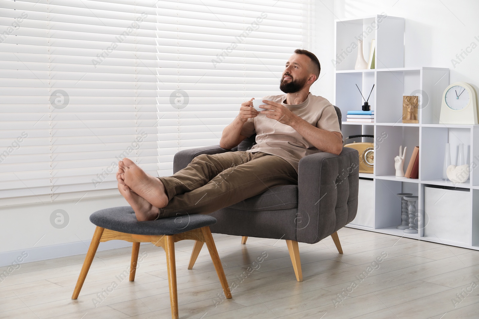 Harmony. Man with cup of drink in armchair at home Photo of Harmony. Man with cup of drink in armchair at home