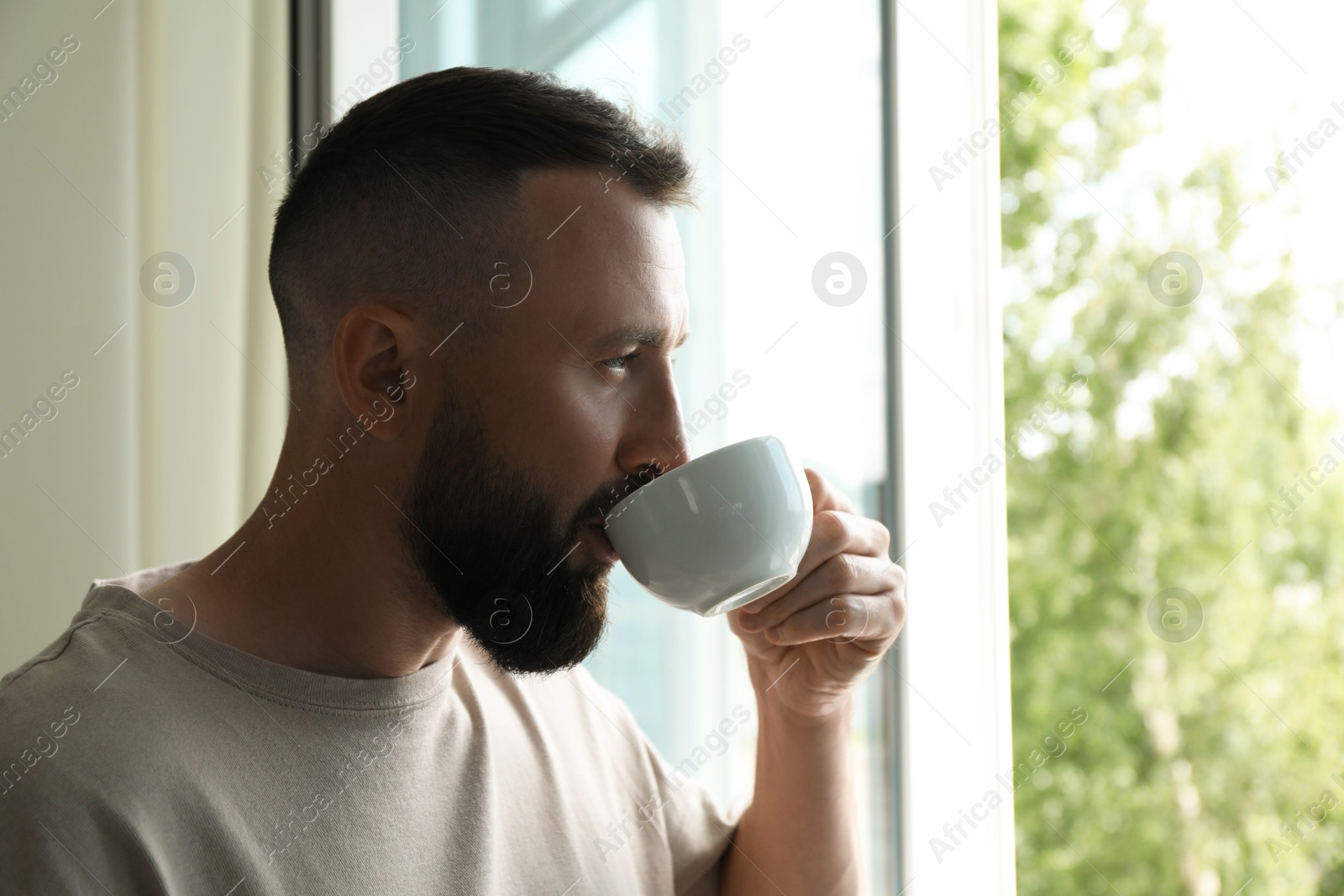 Harmony. Man drinking tea near window at home Photo of Harmony. Man drinking tea near window at home