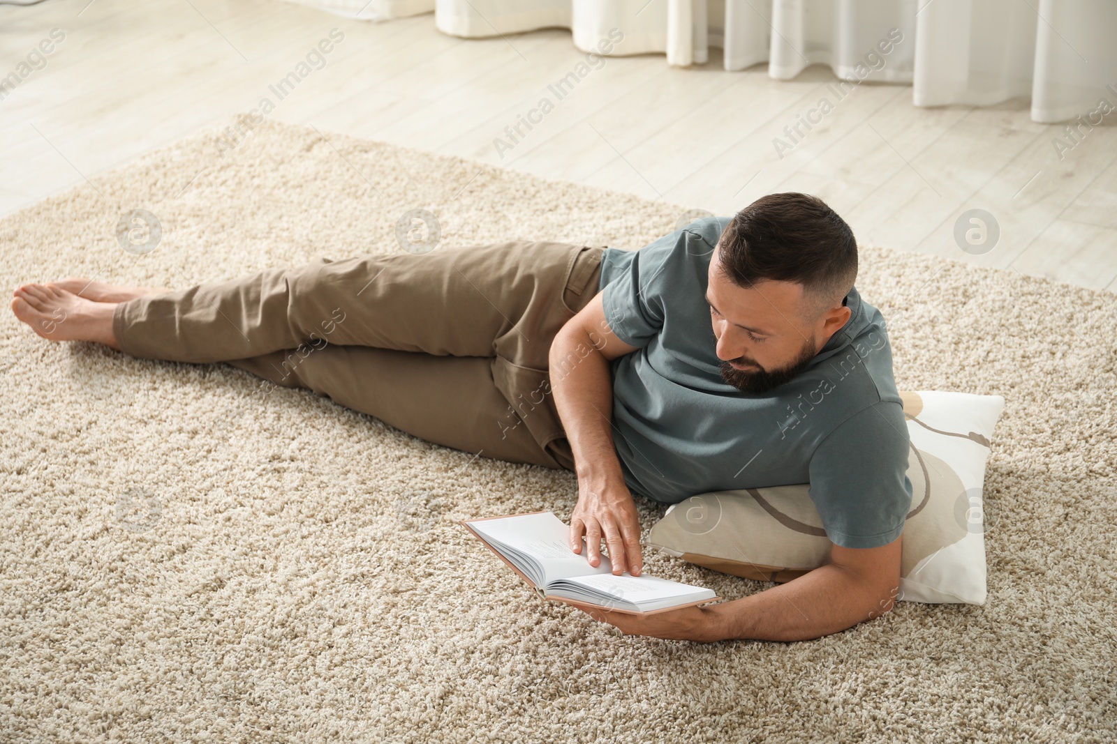 Harmony. Man reading book on rug at home Photo of Harmony. Man reading book on rug at home