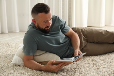 Photo of Harmony. Man reading book on rug at home
