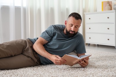 Photo of Harmony. Man reading book on rug at home