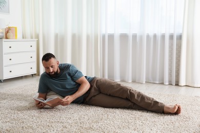 Photo of Harmony. Man reading book on rug at home