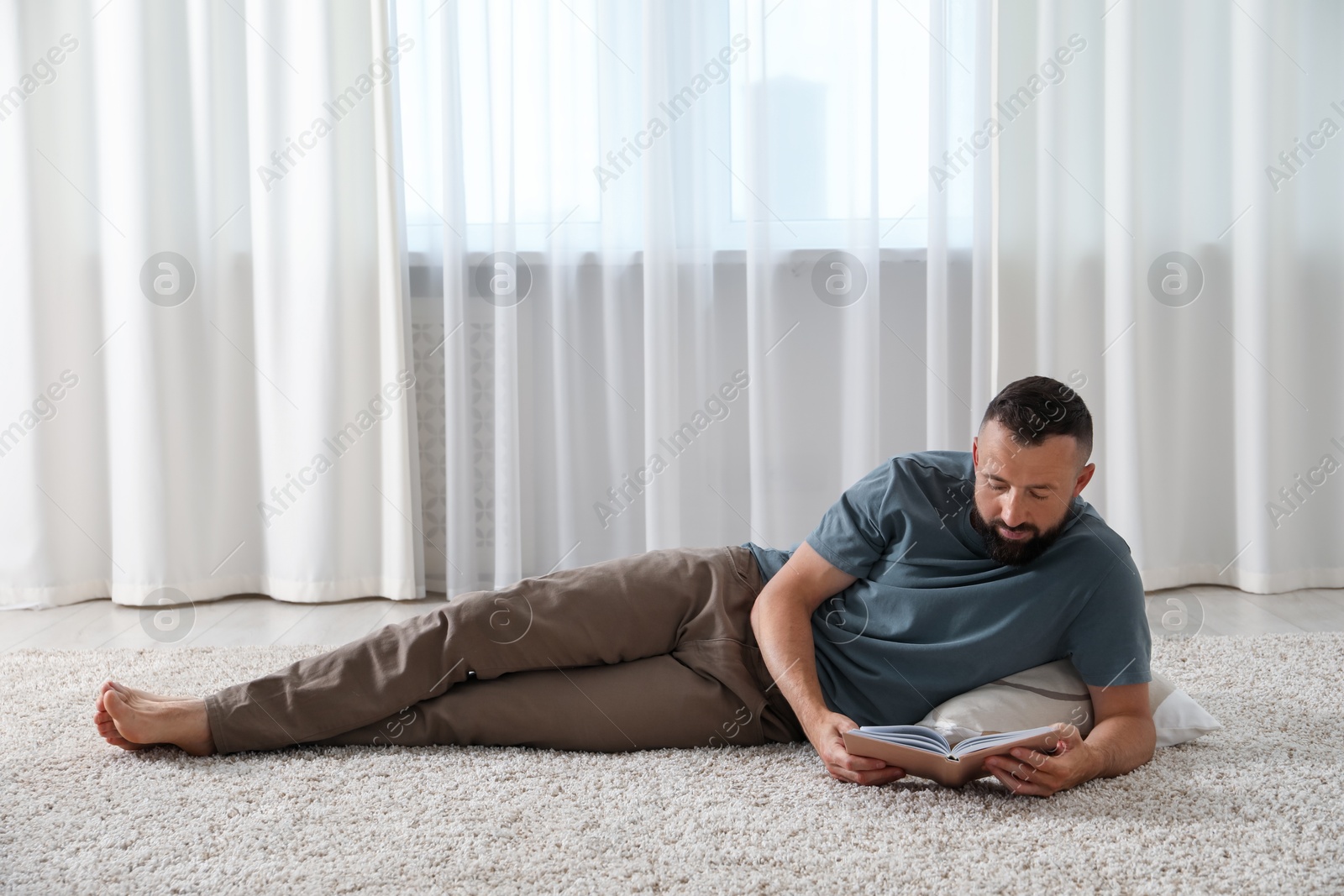 Harmony. Man reading book on rug at home Photo of Harmony. Man reading book on rug at home