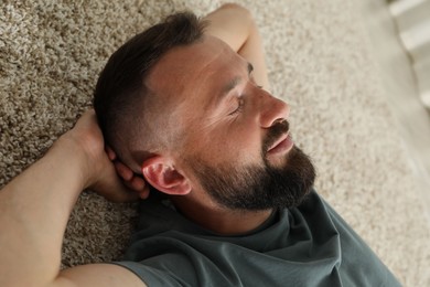 Photo of Harmony. Man lying on rug at home, closeup