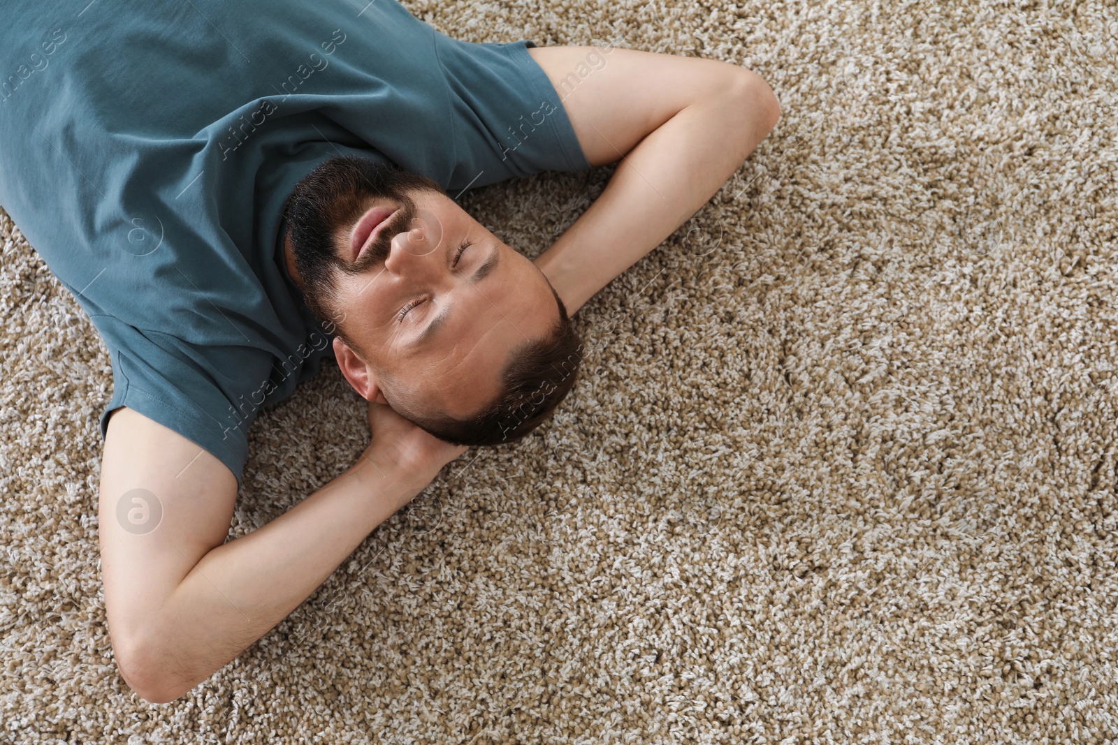 Harmony. Man lying on rug at home, top view Photo of Harmony. Man lying on rug at home, top view