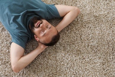 Photo of Harmony. Man lying on rug at home, top view