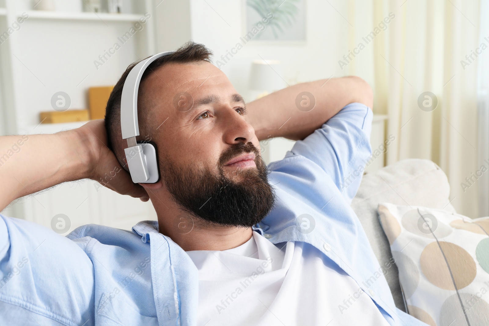 Harmony. Man listening to music in headphones on sofa at home Photo of Harmony. Man listening to music in headphones on sofa at home