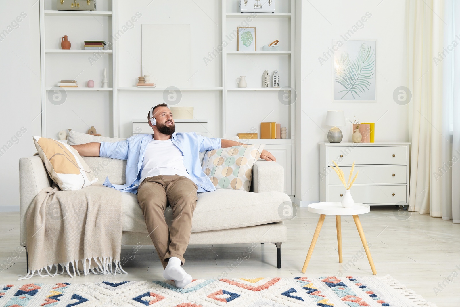 Harmony. Man listening to music in headphones on sofa at home Photo of Harmony. Man listening to music in headphones on sofa at home